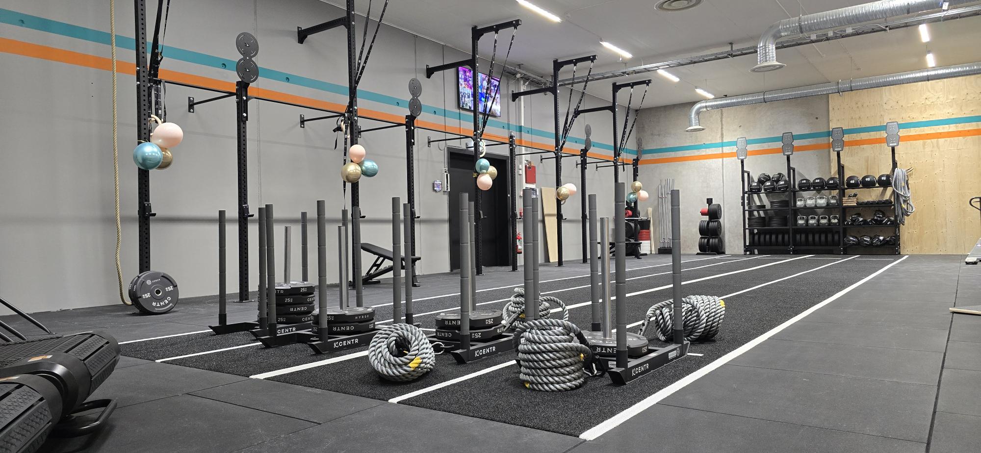 Bildcollage som presenterar 'OFFICIAL HYROX GYM' hos Endorfin, med träningsanläggningar i Alingsås och Lerum. Översta raden visar tre bilder: till vänster en kvinna som tränar med en roddmaskin, i mitten en rad med människor som använder roddmaskiner i synkroniserad takt, till höger några deltagare som utför box jumps. Nedre raden: till vänster en kvinna som gör en battlerope-övning, i mitten en kvinna i rörelse på en löpbandsträning, och till höger ser vi en låg vinkelvy av en sprintbana. Centralt i collage är 'OFFICIAL HYROX GYM' logotypen i gult och vitt mot en svart bakgrund, vilket förstärker Endorfins varumärkesidentitet.